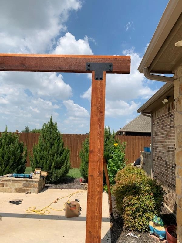 Close-up of a stained cedar beam with a black iron bracket
