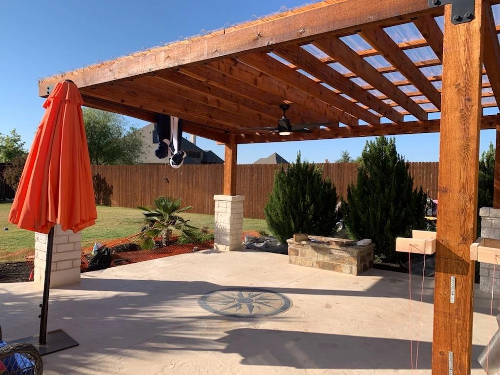 Finished cedar pergola patio cover on stone masonry columns with a ceiling fan and string lights