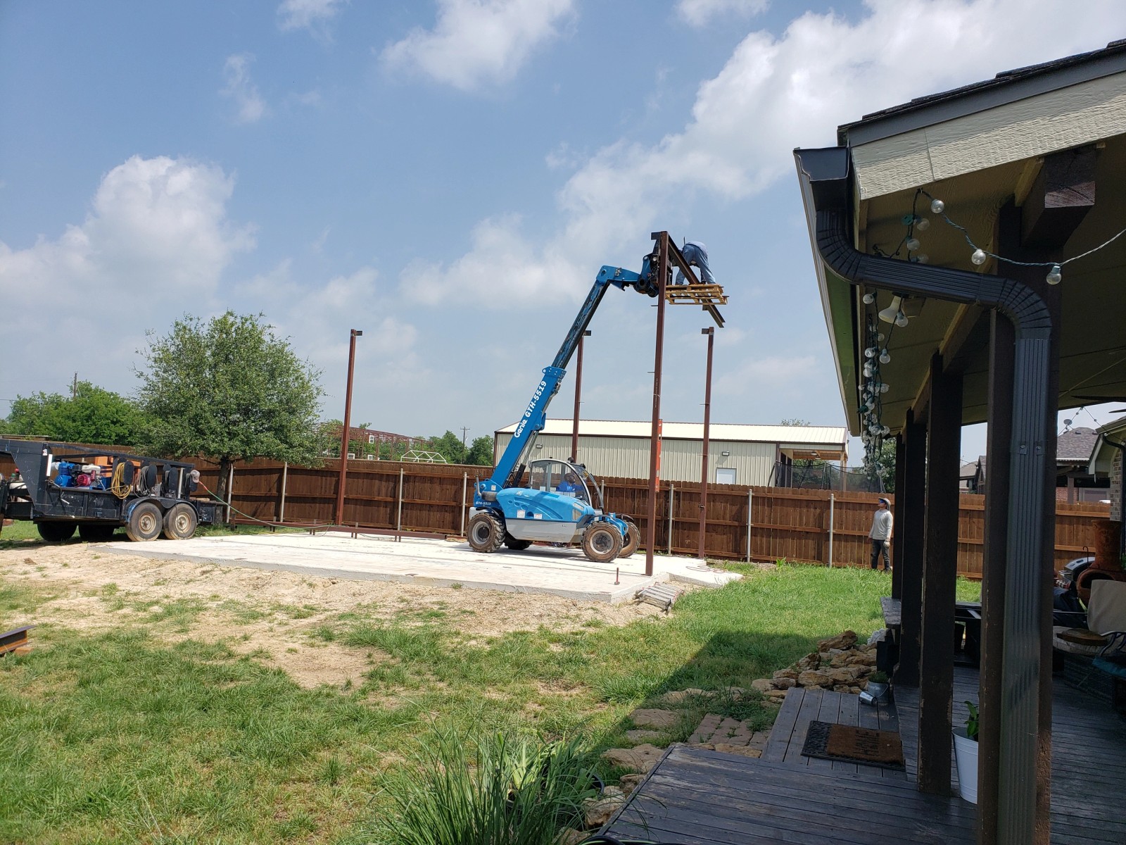 Telehandler crane setting steel frame posts on a fresh concrete slab